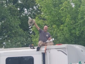 Walt on A Roof waving a hat